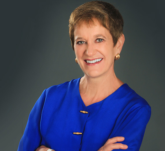 男性がレンガの壁に寄りかかり、背後には桜の木が広がる